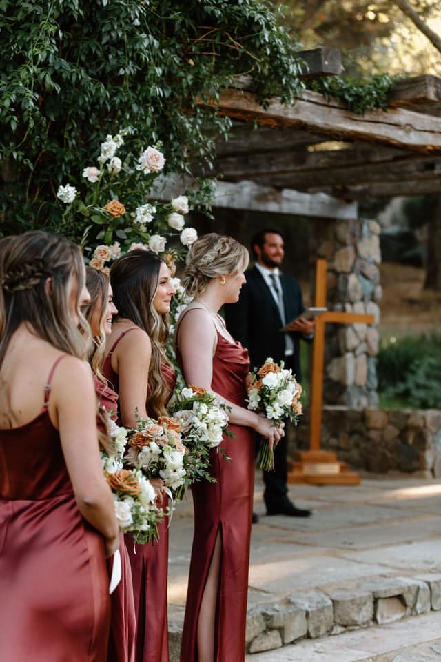 bridesmaids in maroon gowns holding neutral colored bouquets